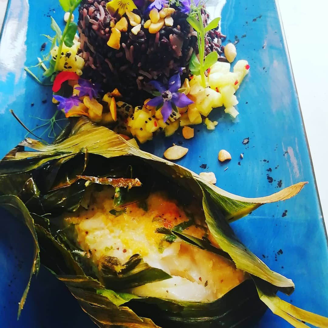 A colourful dish on a blue plate, decorated with edible flowers.