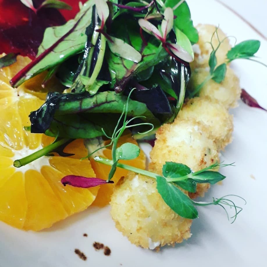 Crisp-coated round bites with orange segments and dressed leaves.