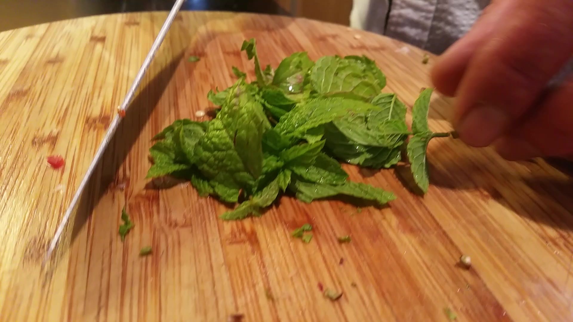 Hands chopping fresh herbs on a wooden board.