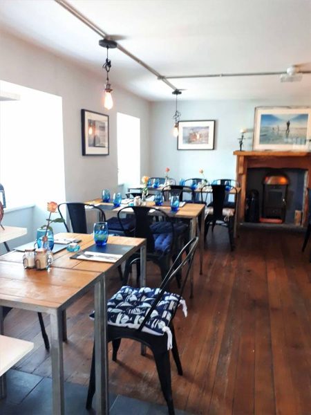 A long dining room with set tables and blue chairs.