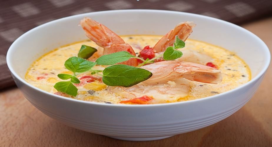 A bowl of creamy soup with king prawns and fresh herbs.
